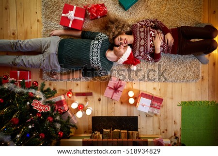 Man and woman lying on the floor in Christmas decorated home