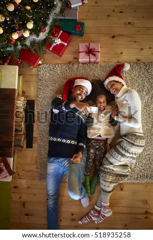 Christmas atmosphere, young family lying on floor their wooden home and making selfie