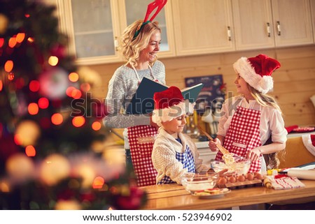 smiling mother and children baking cookies at home on Xmas eve