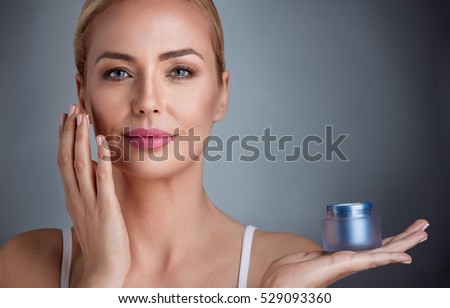Beautiful nourished woman holding cream for her skin