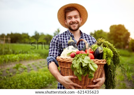 Nice young farmer with freshly picked vegetables in basket
