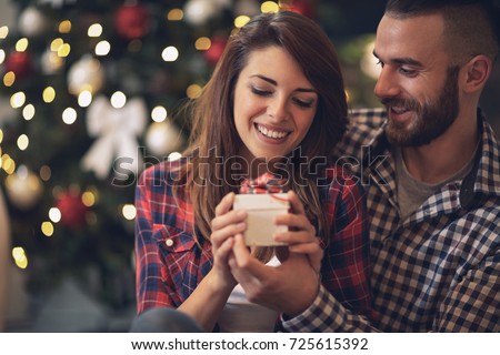 Young woman with husband looking at Christmas gift