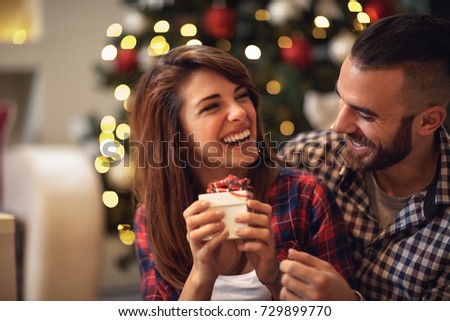 Cheerful couple with gift in hands enjoying together on Christmas eve