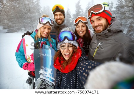 winter, extreme sport and people concept - happy friends having fun on the snow and making selfie