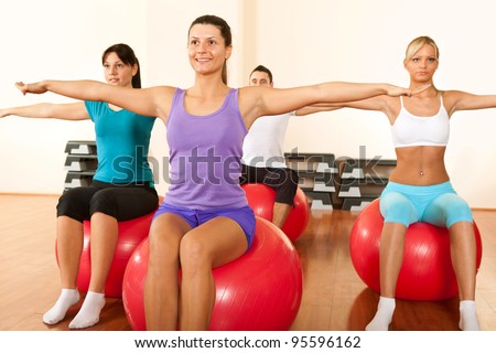 group of young  people in a pilates class exercising with balls