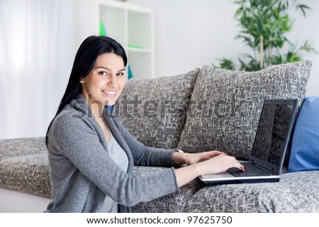 Woman sitting on floor  working with computer at home in  living room.