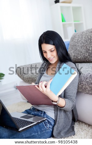 young girl with learning at home, sitting on floor and holding  laptop and books