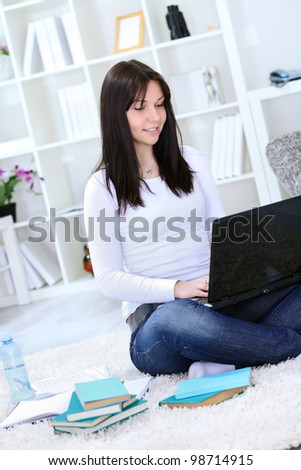 Smiling student sitting on floor with laptop and learning
