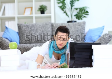 Young female student  with books and laptop learning at home