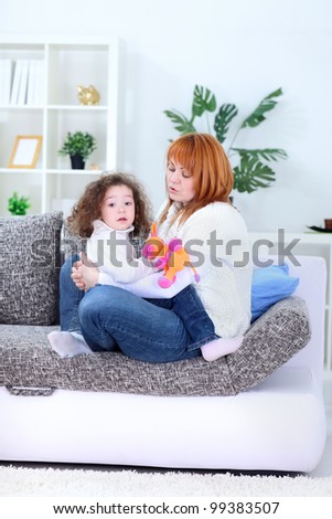 Young mother lying on the sofa and playing with her happy loving little daughter  indoor