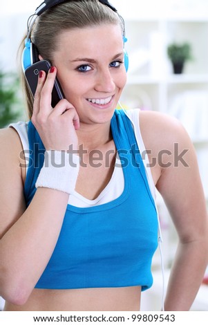 Young smiling girl in sportswear using Mobil phone