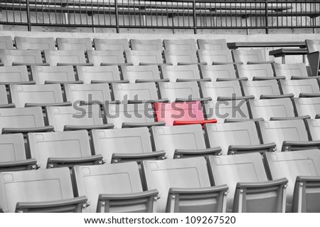 A field of empty stadium seats only one seat is red