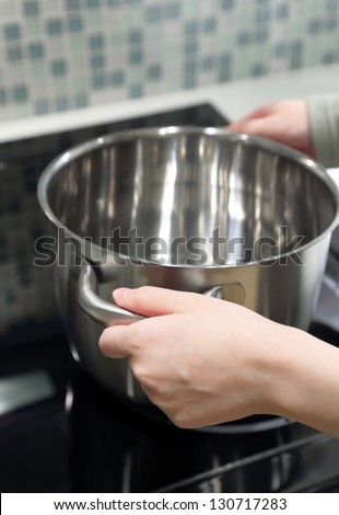 Woman putting a pan on oven, focus on front hand