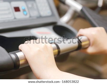 Focus on left hand of woman on running machine