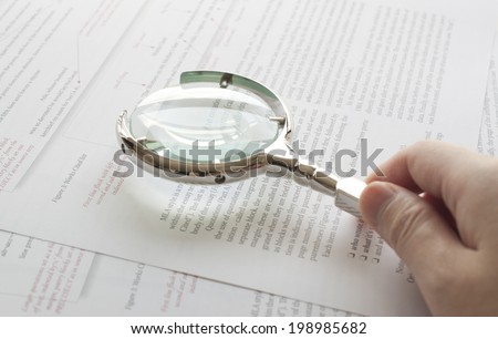 Coquitlam BC Canada - June 09, 2014 : Close up hand holding magnifying glass to read document in Coquitlam BC, Canada.