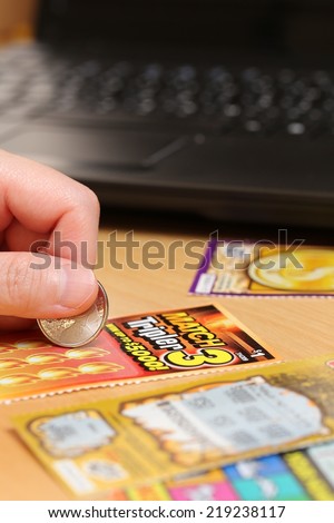 Coquitlam BC Canada - June 15, 2014 : Woman scratching lottery ticket called Match 3 tripler with computer and lottery ticket background. It\'s published by BC Lottery Corporation.