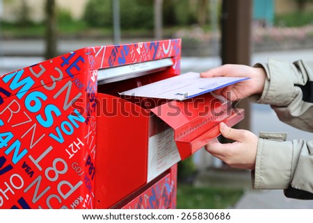 Coquitlam, BC Canada - April 24, 2014 : Hand sending a tax report letter in a red mail box