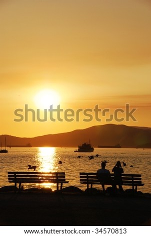 Silhouette of a couple enjoy beautiful sunset view in English Bay, Vancouver BC Canada