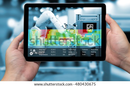 Industry 4.0 concept .Man hand holding tablet and Blue tone of Augmented reality screen with automate wireless Robot arm for measurement temperature software in smart factory blur background