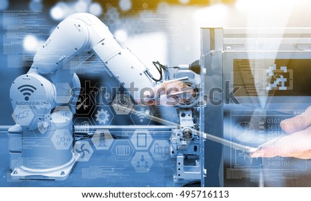 Industry 4.0 concept .Business man holding tablet with industry graphic sign and blue tone of automate wireless Robot arm in smart factory background. Double exposure , blue tone , flare light