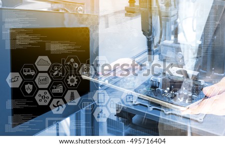 Industry4.0 concept .Business man holding tablet with industry graphic sign and blue tone of automate wireless Robot arm in smart factory background. Double exposure , blue tone , flare light