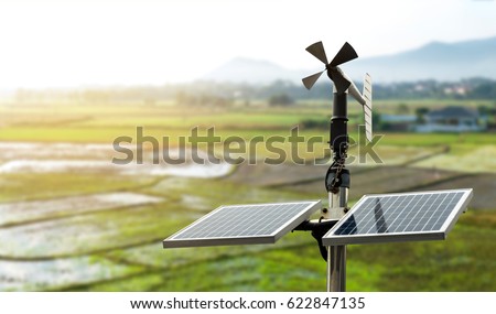 Smart agriculture and smart farm technology concept. Revolving vane anemometer, a meteorological instrument used to measure the wind speed and solar cell system with rice field background.
