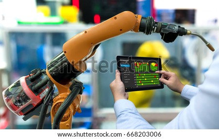 Engineer manager hand using tablet, heavy automation robot arm machine in smart factory industrial with tablet real time monitoring production system. Industry 4th iot concept.