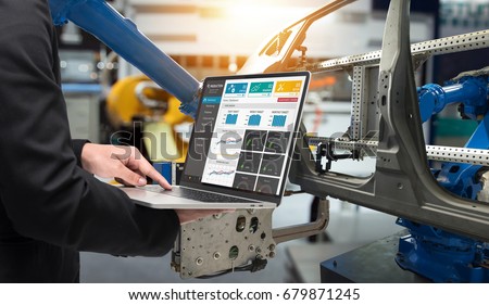 Male manager hand laptop for check real time production monitoring system application in smart factory industrial. Automobile manufacturing production machine , robot arm. industry 4.0 concept.