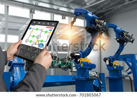 Engineer hand using tablet, heavy automation robot arm machine in smart factory industrial with tablet real time process control monitoring system application. Industry 4th iot concept.