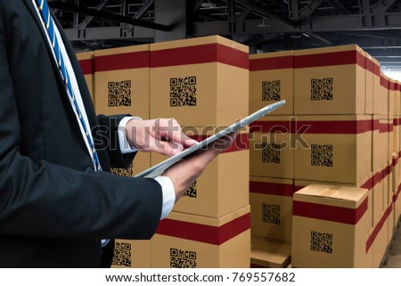 Smart logistic industry 4.0 , QR Codes Asset warehouse and inventory management supply chain technology concept. Businessman using tablet and group of boxes in storehouse can check product inside.