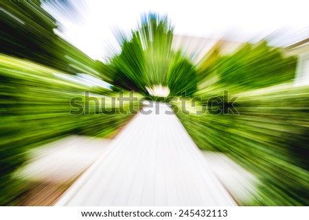 Image of bricks pathway and green trees in the park, motion blur effect
