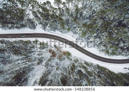 Aerial view of snowy forest with a road. Captured from above with a drone