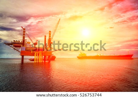 Silhouette of an offshore drilling rig and an orange sunset