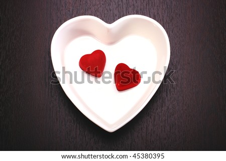 heart shaped chocolates in white heart dish on dark surface