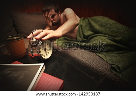 man with sad expression touch clock in early morning