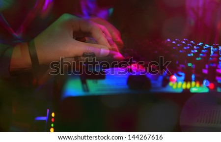 close-up dj hand in colorful disco night