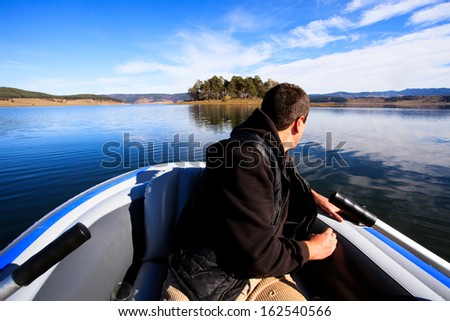 man in boat sailing to small island in bulgarian lake