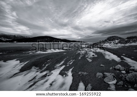 high contrasted black and white winter landscape  the beach on high mountain lake covered with snow