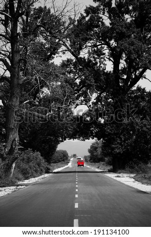 abstract black and white road with single red car in distance