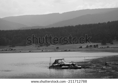 black and white landscape with boat in calm high mountain lake