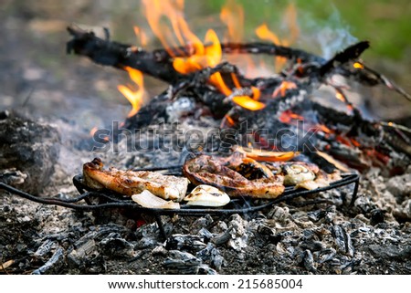 hand-made bbq in forest with beacon and vegetable covered with flames