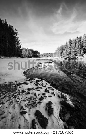 high contrasted vertical black and white winter landscape with frozen high mountain lake