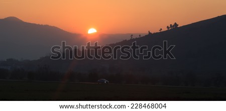 low light sunset landscape with car traveling in bulgarian country road