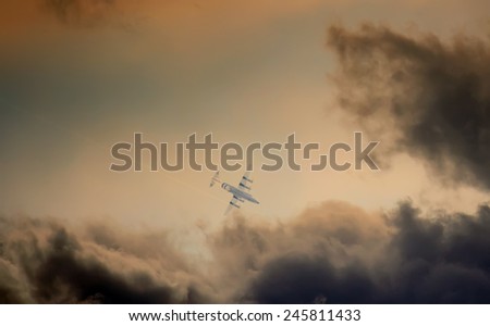airplane flying close to the storm in sunset time