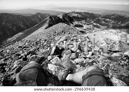 black and white landscape with man legs in unusual perspective on high mountain peak
