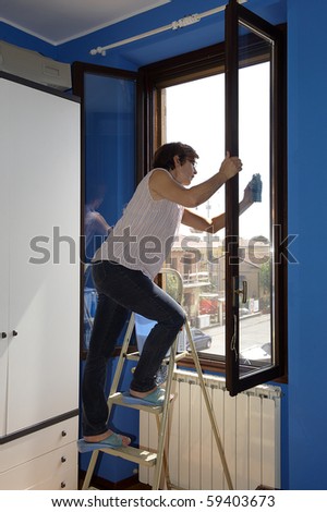 A woman cleans the windows of the house