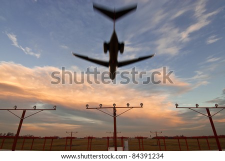Commercial airliner landing at dusk from end of runway