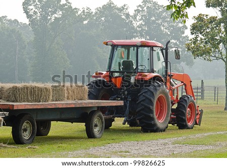 Red tractor hauling bales of hay