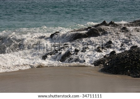 Foamy sea water flushing over rocks on beach