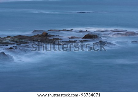Long exposure image showing misty blue water flowing over rocks with negative space for graphics.